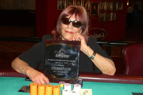 Poker player Barbara Enright holding a champion plaque at the table with chip stacks